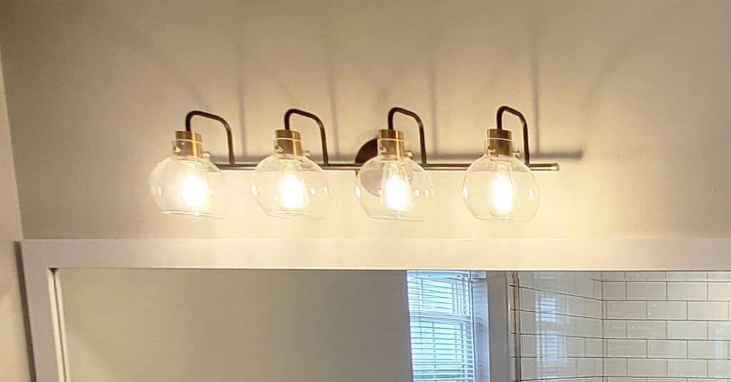 Bathroom lighting ideas - sconces light with 4 bulbs over the bathroom mirror and sink